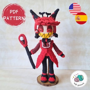 Puede incluir: Juguete de amigurumi tejido a crochet de un personaje de diablo rojo con cuernos, una pajarita negra y un bastón negro. El juguete está de pie sobre una base de madera. La imagen incluye el texto "PDF PATTERN".