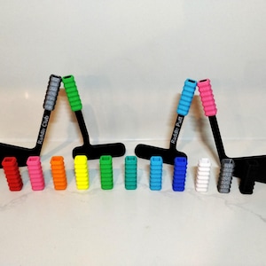 May include: A set of 14 colorful, textured, foam grips for a hockey stick. The grips are in various colors, including red, pink, orange, yellow, green, blue, and white. The grips are labeled "Raddin Club" and "Raddin Putt".