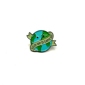 May include: Green and blue enamel pin of a cartoon Earth with a smiling face and a banner that reads "Every Day is Earth Day."
