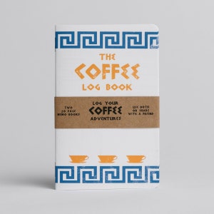 Puede incluir: Un cuaderno blanco con un dise&ntilde;o de llave griega azul y blanco en la portada. El cuaderno se titula "The Coffee Log Book" y tiene una banda de papel marr&oacute;n que dice "Log Your Coffee Adventures".