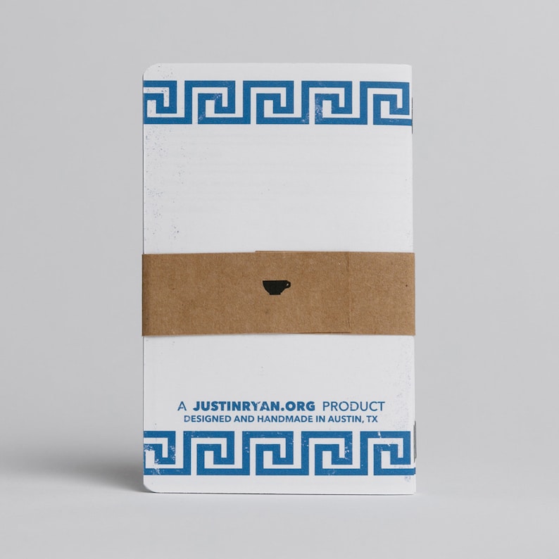 Puede incluir: Un cuaderno blanco con un borde azul de clave griega y una banda de papel marr&oacute;n con un peque&ntilde;o icono de taza de caf&eacute;. El texto "A JUSTINRYAN.ORG PRODUCT DESIGNED AND HANDMADE IN AUSTIN, TX" est&aacute; impreso en el cuaderno.