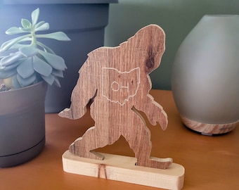May include: Wooden cutout of Bigfoot standing on a wooden base. The cutout is brown and has the state of Ohio with the word "OHIO" inside it.