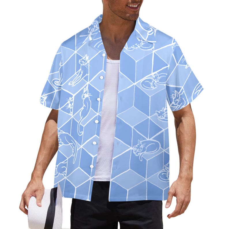 Puede incluir: Camisa azul claro de manga corta con un patr&oacute;n geom&eacute;trico de cubos e ilustraciones de gatos blancos. La camisa tiene un cuello cl&aacute;sico y se lleva abierta.