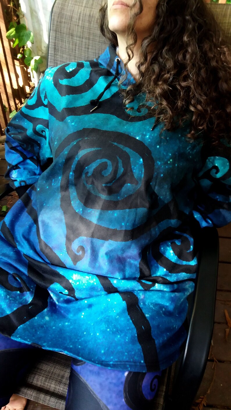May include: A blue and black hooded sweatshirt with a galaxy print and a swirling pattern. The hoodie has a drawstring and a relaxed fit.