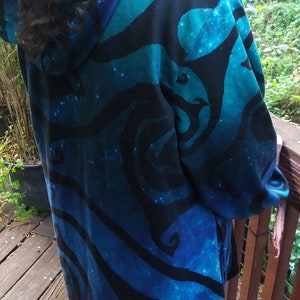May include: A hooded jacket with a blue and black swirling pattern. The jacket is made of a soft, comfortable fabric and has a relaxed fit.