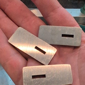 Könnte beinhalten: Drei rechteckige Schlüsselrohlinge aus silbernem Metall mit einem Schlitz in der Mitte.