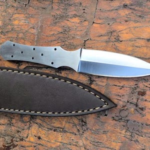 May include: A silver dagger with a brown leather sheath. The dagger has a double-edged blade and a handle with multiple holes.