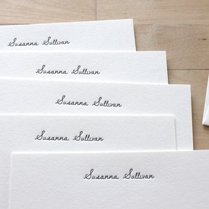 May include: Five white stationery cards with the name "Susanna Sullivan" written in cursive on each card.
