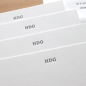 May include: Four white cards stacked on top of each other. Each card has the letters "HDG" printed in black ink.