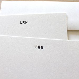 May include: White stationery set featuring two notecards and an envelope. Each card is embossed with the initials "LRH" in black, centered at the top. The paper has a textured finish, and the set is arranged on a light wood surface.