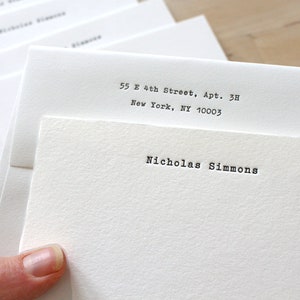 May include: A stack of white envelopes with a typed address and name. The address reads "55 E 4th Street, Apt. 3H, New York, NY 10003". The name reads "Nicholas Simmons".