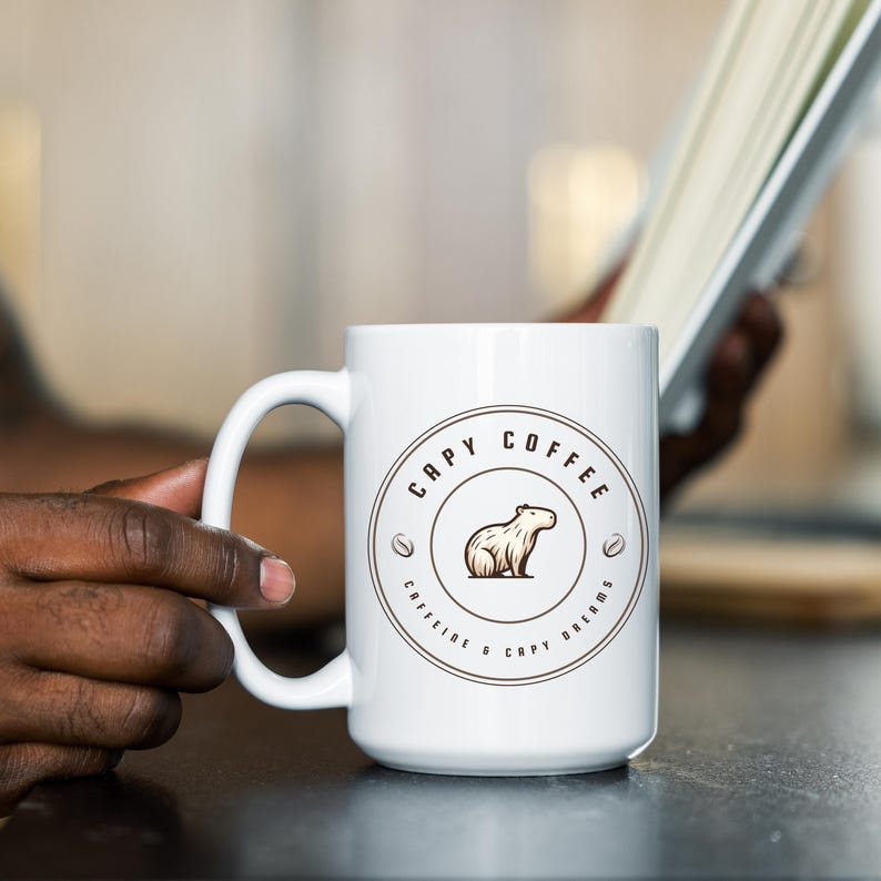 May include: White ceramic coffee mug with a brown graphic of a capybara and the text "Capy Coffee Caffeine & Capy Dreams".