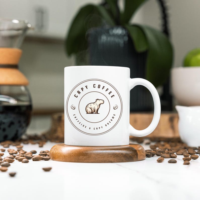 May include: White ceramic mug with a brown circle design featuring a capybara and the text "Capy Coffee Caffeine & Capy Dreams".