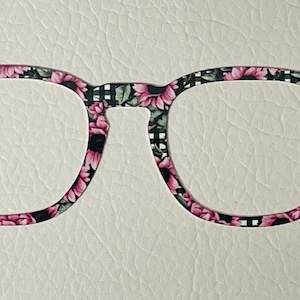 May include: A pair of black and white glasses with a pink floral pattern.