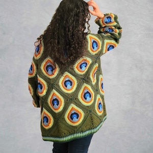 May include: A green crocheted cardigan with a peacock eye pattern in shades of blue, orange, and yellow. The cardigan has a loose fit and long sleeves.
