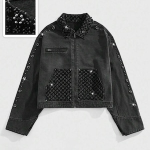 May include: A black denim jacket with a collared neckline, zip-up front, and two front pockets. The collar, pockets, and sleeves are embellished with sparkling rhinestones. The jacket has a cropped fit and long sleeves.