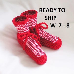 May include: A pair of red crochet slippers with white zigzag patterns and matching red ties. The slippers have a cuff and are designed for women's sizes 7-8.