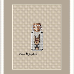 May include: A cross-stitch pattern of a hand making the rock and roll hand gesture inside a glass bottle with a cork top. The artist's name, Irina Konoplich, is written below the bottle.