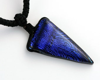 May include: A dark blue glass pendant with a textured surface, hanging from a black cord.