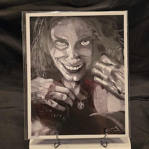 Puede incluir: Ilustración en blanco y negro de una mujer con cabello largo y oscuro, vistiendo una blusa oscura y un collar con un colgante. Tiene una sonrisa siniestra y sus manos están levantadas hacia su rostro.