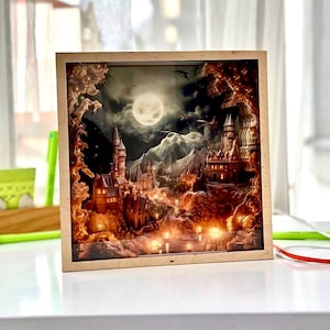 May include: A wooden shadow box featuring a 3D image of a castle set against a snowy landscape. The castle is illuminated with warm lights and a full moon hangs in the sky.