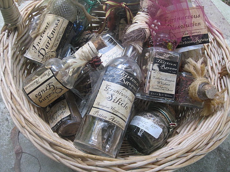 May include: A wicker basket filled with small glass bottles containing various potions. The bottles have labels with handwritten text, including "Instant Darkness", "Grubs Oozing", "Thirteen Ravens", "Farinaceous Dissolution", and "Granivorous Silicle".