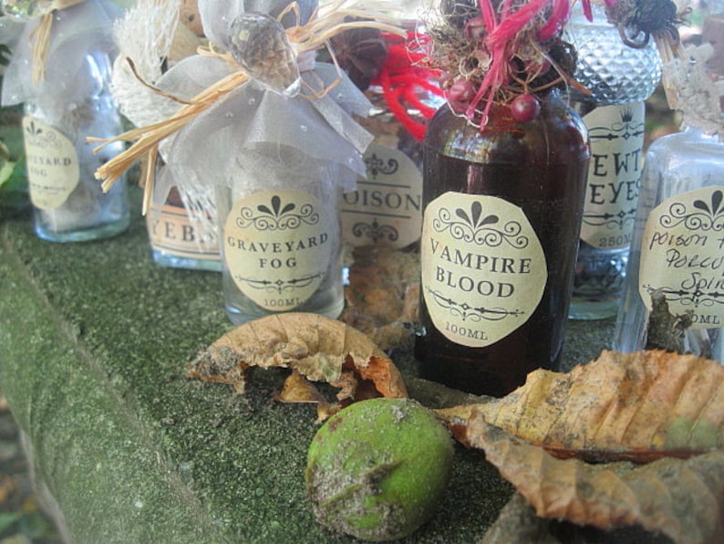 May include: A collection of small glass bottles with labels that read "Graveyard Fog", "Vampire Blood", "Ewt Eye", and "Poison Porco Spirit". The bottles are filled with a variety of liquids and are decorated with various embellishments, including a small, white, lace-like bow.