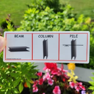 May include: A white card with black text and illustrations showing the difference between a beam, column, and pile. The text on the card reads "BEAM", "COLUMN", and "PILE".
