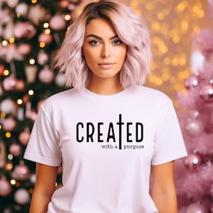 May include: White t-shirt with black text that reads "CREATED with a purpose" and a cross symbol.