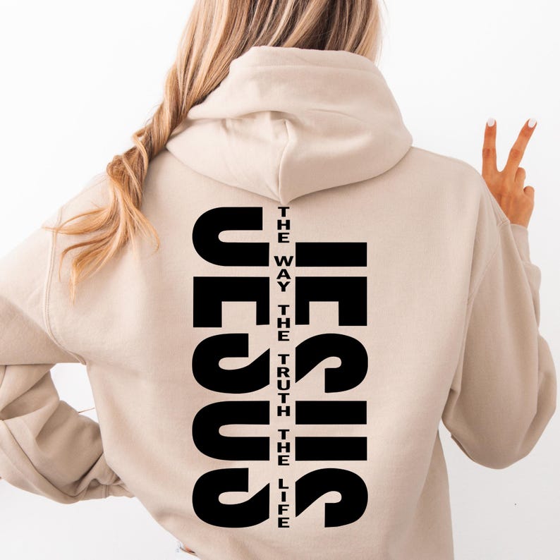 May include: A beige hoodie with the word "JESUS" printed vertically on the back. The text is in black and reads "THE WAY THE TRUTH THE LIFE"