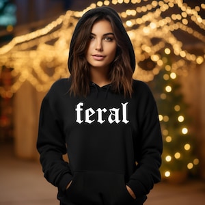 May include: A black hooded sweatshirt with the word "feral" printed in white gothic lettering.