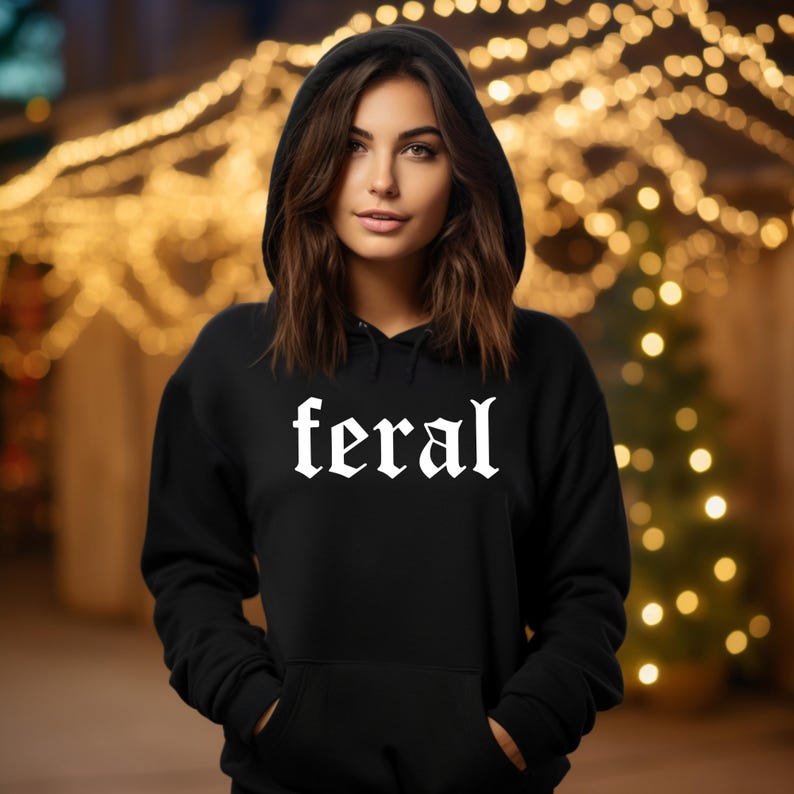 May include: A black hooded sweatshirt with the word "feral" printed in white gothic lettering.