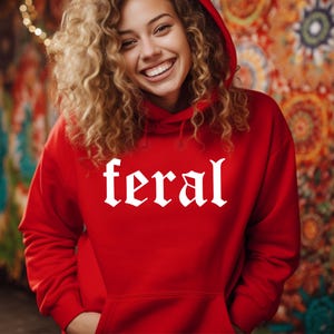 May include: A red hooded sweatshirt with the word "feral" printed in white gothic lettering.