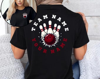 May include: Black t-shirt featuring a bowling design with the text "TEAM NAME" and "YOUR NAME" in white and red. The design includes a bowling ball and pins. A smaller version of the design is on the front of the shirt.