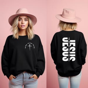 May include: Black sweatshirt with a white cross and the text "The Way The Truth The Life" on the front and the text "JESUS" vertically on the back.