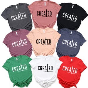 May include: Nine t-shirts in different colors with the text "CREATED with a purpose" and a cross symbol.