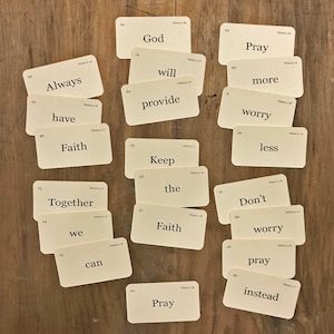 May include: A set of white index cards with black text, each card containing a word or phrase related to faith and prayer. The words include "God", "Pray", "Faith", "Always", "Have", "Together", "We", "Can", "Will", "Provide", "Keep", "The", "More", "Worry", "Less", "Don't", "Pray", and "Instead".