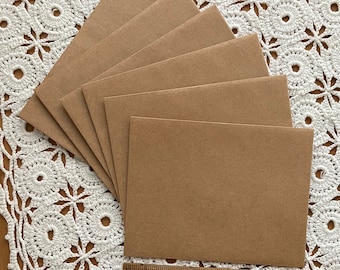 May include: A stack of six brown envelopes, arranged in a fan shape, on a white crocheted doily.