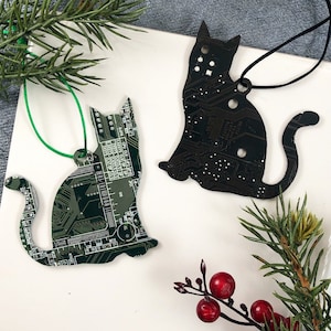 May include: Two black cat ornaments made from recycled circuit boards. One cat is green and the other is black.