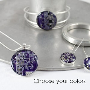 Pode incluir: Um conjunto de joias com designs de placas de circuito roxo. O conjunto inclui um colar, uma pulseira e um par de brincos. Escolha suas cores.