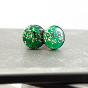 May include: A pair of green and silver cufflinks with a circuit board design.