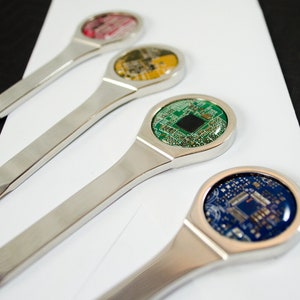 K&ouml;nnte beinhalten: Vier silberne Brief&ouml;ffner mit verschiedenen farbigen Platinen-Designs. Die Platinen sind rot, gelb, gr&uuml;n und blau.