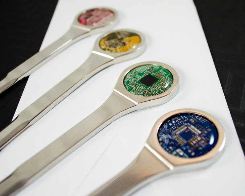 K&ouml;nnte beinhalten: Vier silberne Brief&ouml;ffner mit verschiedenen farbigen Platinen-Designs. Die Platinen sind rot, gelb, gr&uuml;n und blau.