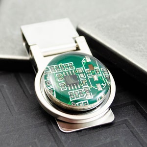 May include: A silver money clip with a round, green, epoxy-filled, circuit board design.