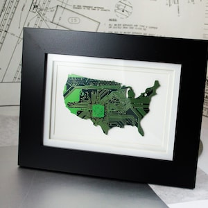May include: A framed artwork featuring a green circuit board shaped like the United States of America.