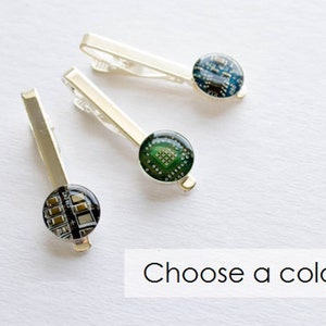 Puede incluir: Tres pasadores de corbata plateados con diseños circulares recubiertos de resina. Cada pasador presenta un patrón de placa de circuito diferente en tonos verdes, azules y negros. El texto "Choose a color" es visible en un rectángulo blanco.