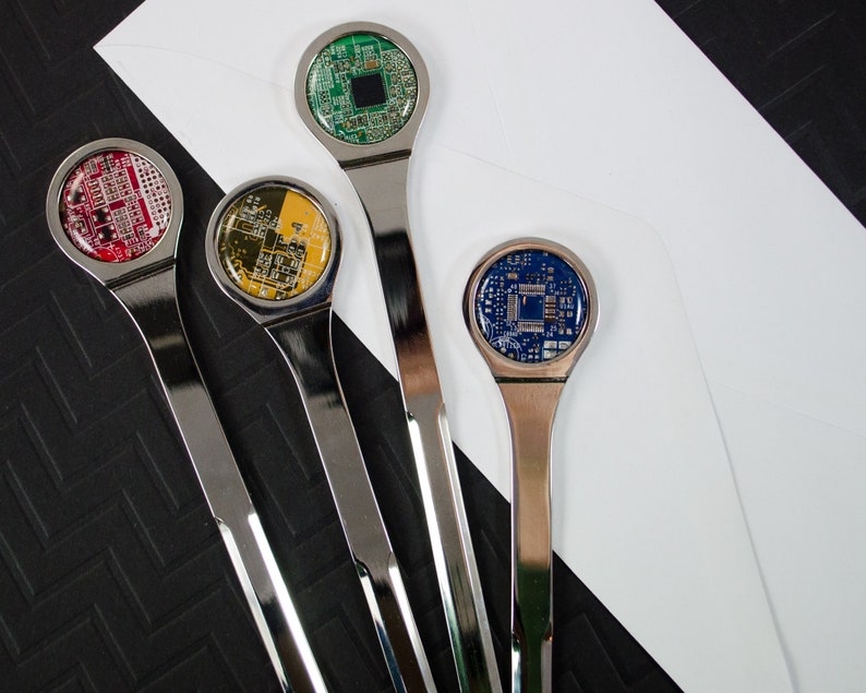 K&ouml;nnte beinhalten: Vier silberne Brief&ouml;ffner mit verschiedenen farbigen Platinen-Designs. Die Platinen sind rot, gelb, gr&uuml;n und blau.