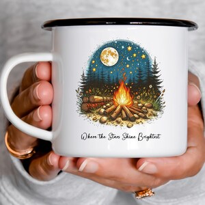 May include: White enamel camping mug with a black rim. The mug features a campfire scene with a full moon, stars, and trees. The text "Where the Stars Shine Brightest" is printed on the mug.
