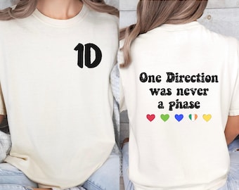 May include: A white t-shirt with the number "1D" printed on the front and the text "One Direction was never a phase" printed on the back. The back also features five small hearts in different colors.