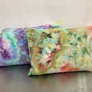 May include: Two tie-dye pillowcases, one in shades of purple, blue, and green, and the other in shades of green, yellow, and orange.